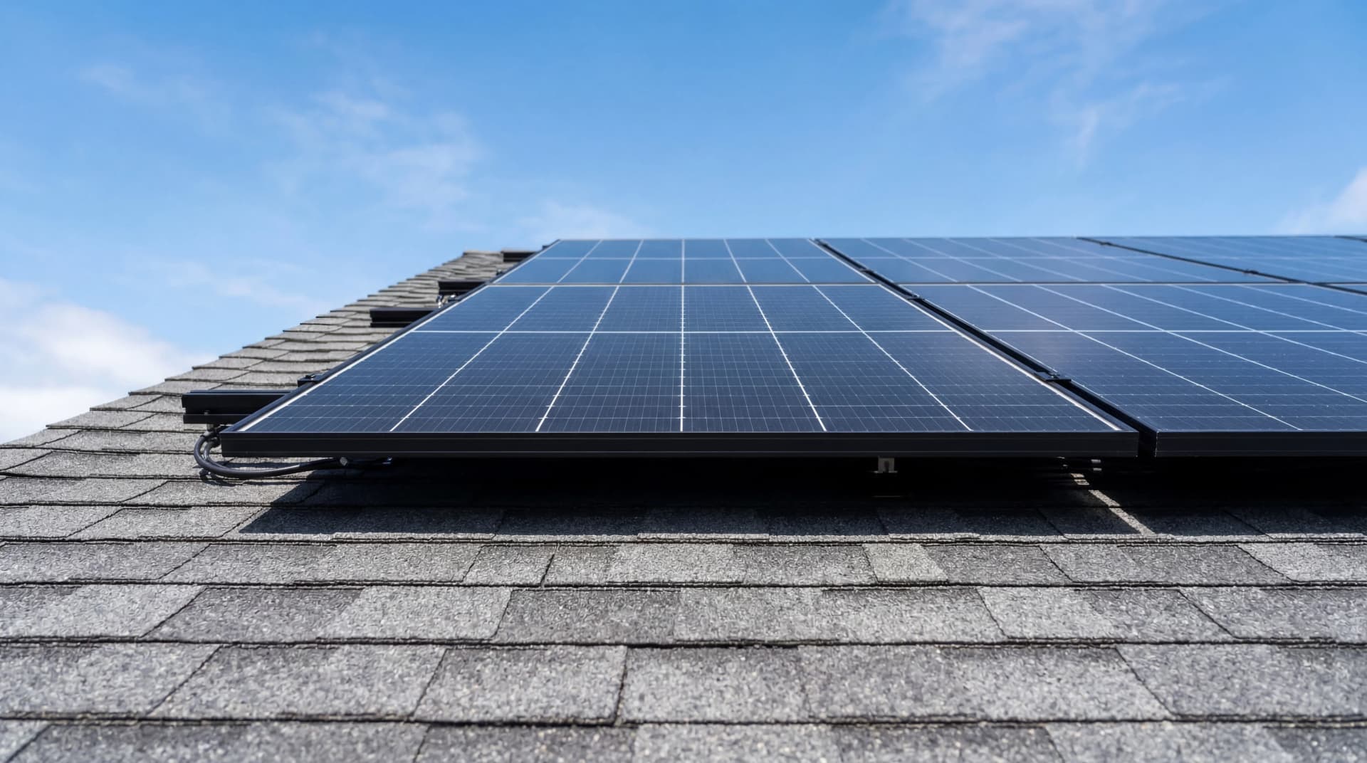 Close-up of premium all-black solar panels installed on gray shingle roof